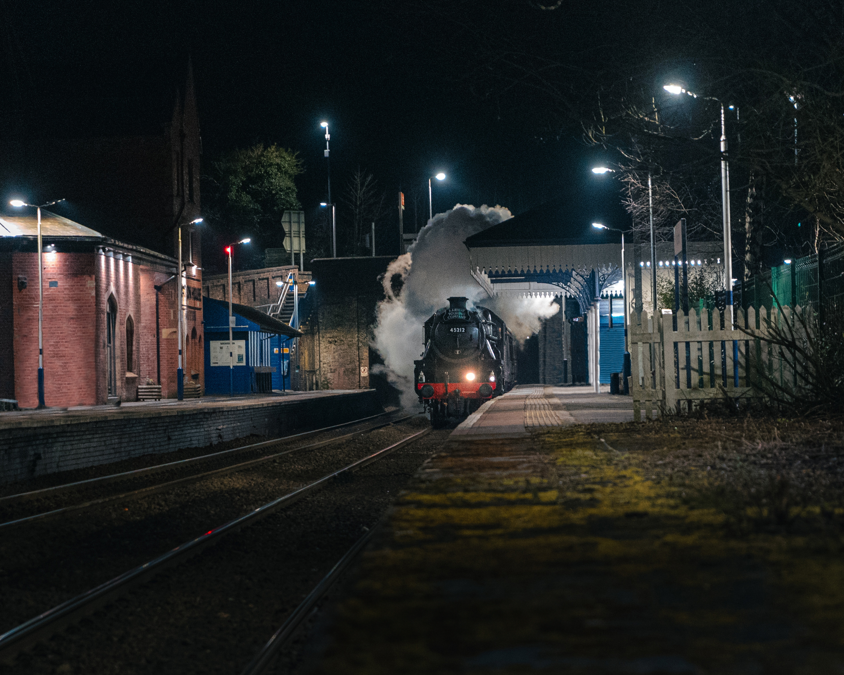 A moody image of a steam train passing through a train station